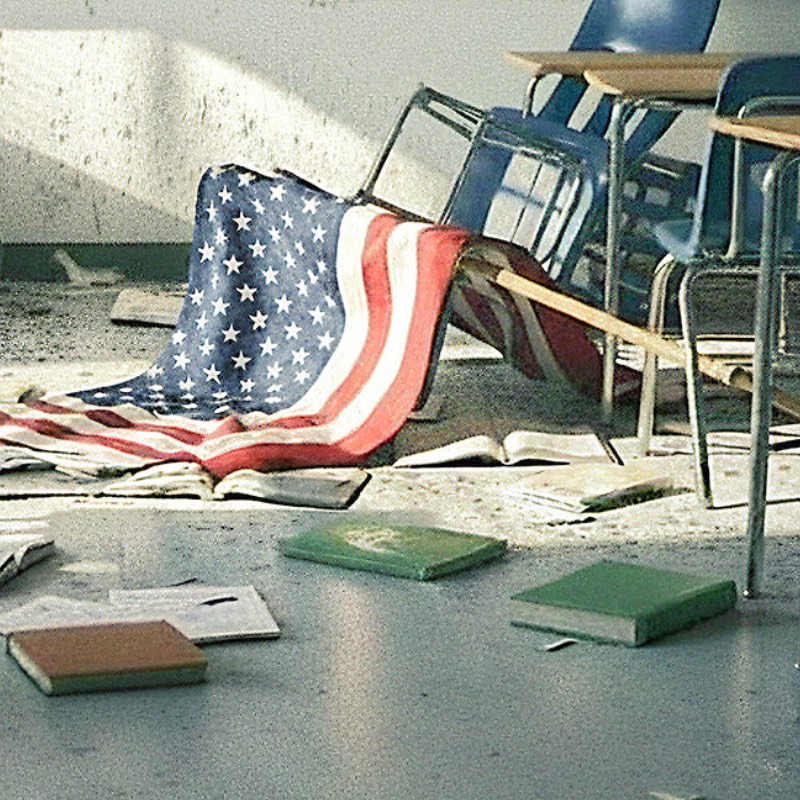 A detail of the wrecked classroom: an American flag draped over a toppled chair, with textbooks and papers scattered across the floor.